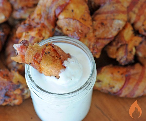 bacon wrapped chicken wing dunked in blue cheese dip