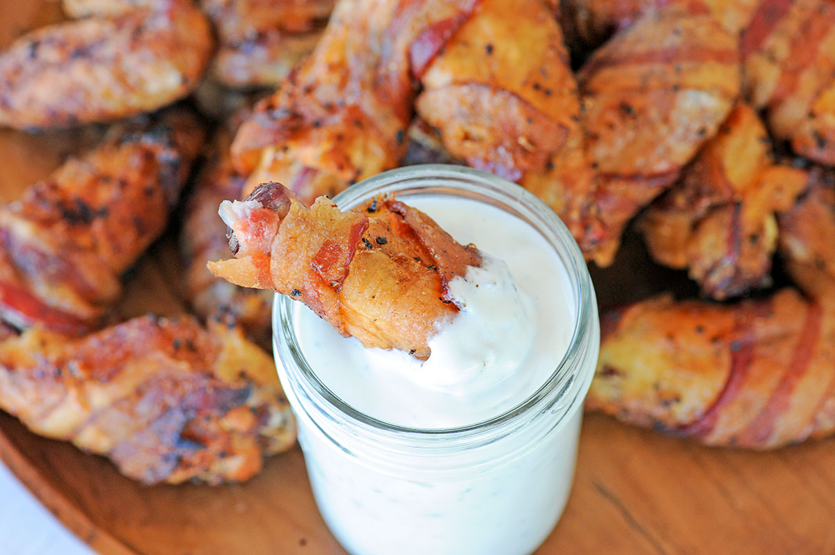 bacon wrapped chicken wing dunked in blue cheese.