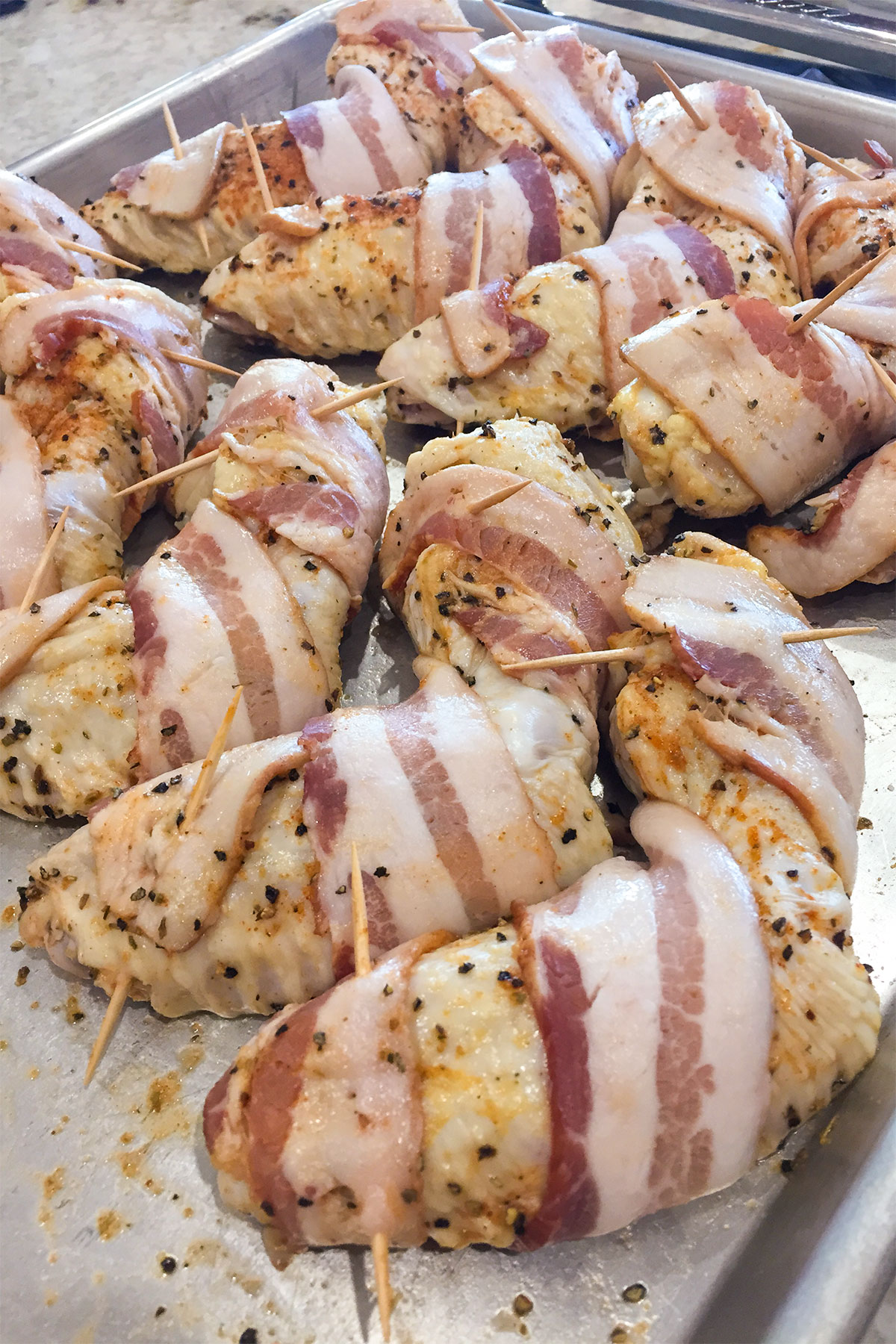 bacon wrapped around seasoned chicken wings secured with toothpicks.