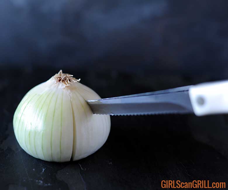 knife point near top of onion root slicing down