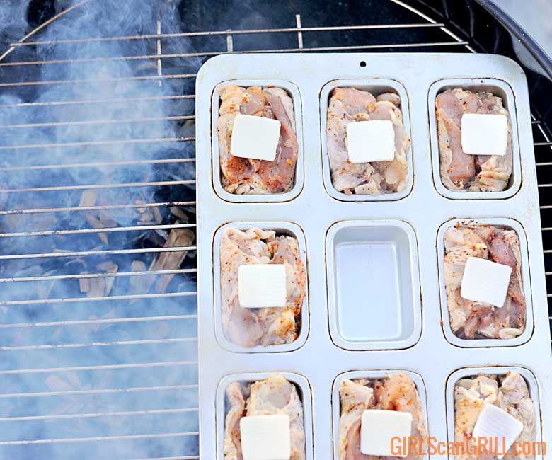 chicken thighs smoke in a mini loaf pan on top of a grill grate