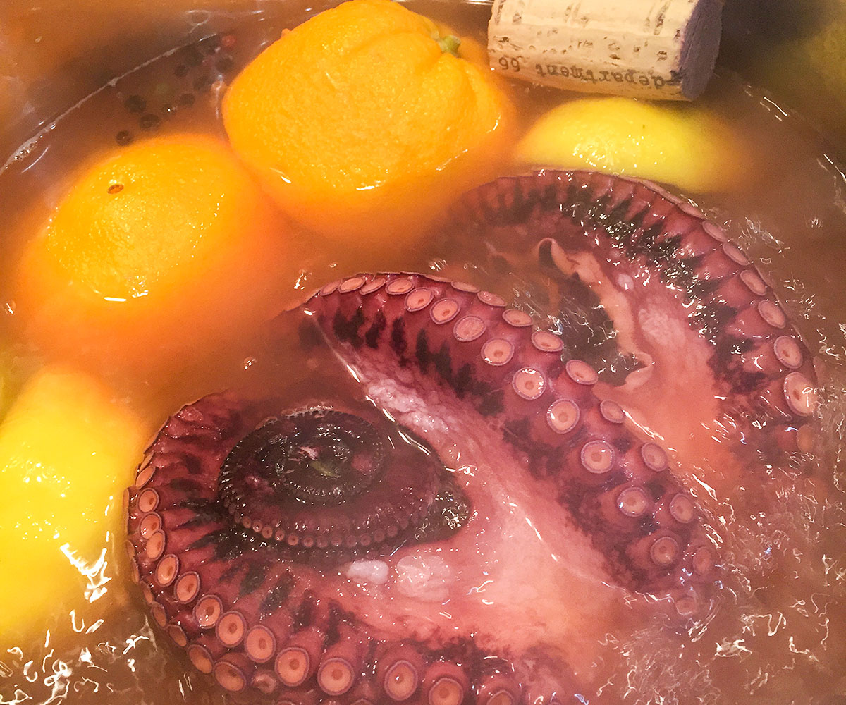 whole octopus in pot of water with citrus and a cork.