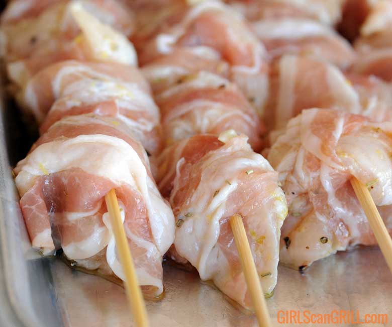 close up of chicken wrapped in pancetta on skewers