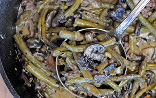 green bean casserole in a cast iron pan with large spoon