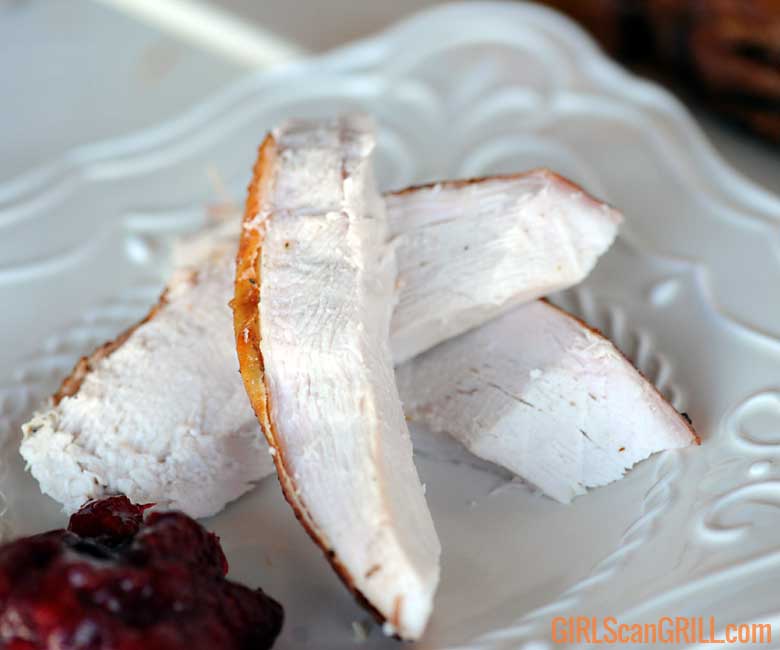white plate with three strips of sliced turkey breast and cranberry sauce