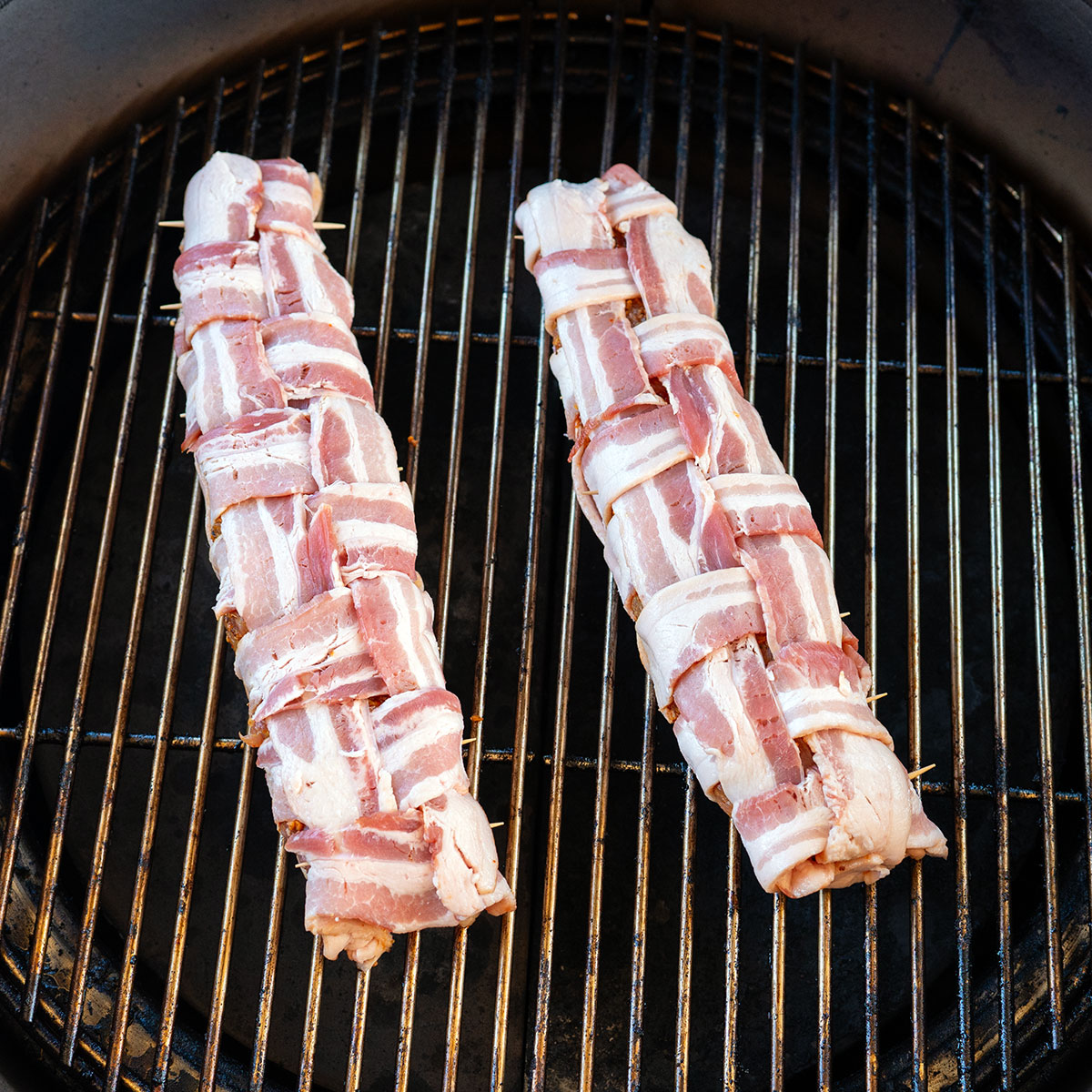 two bacon-wrapped pork tenderloins on grill.
