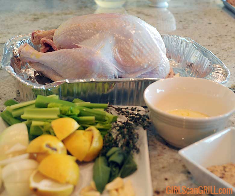 raw turkey in pan near sliced lemons and celery