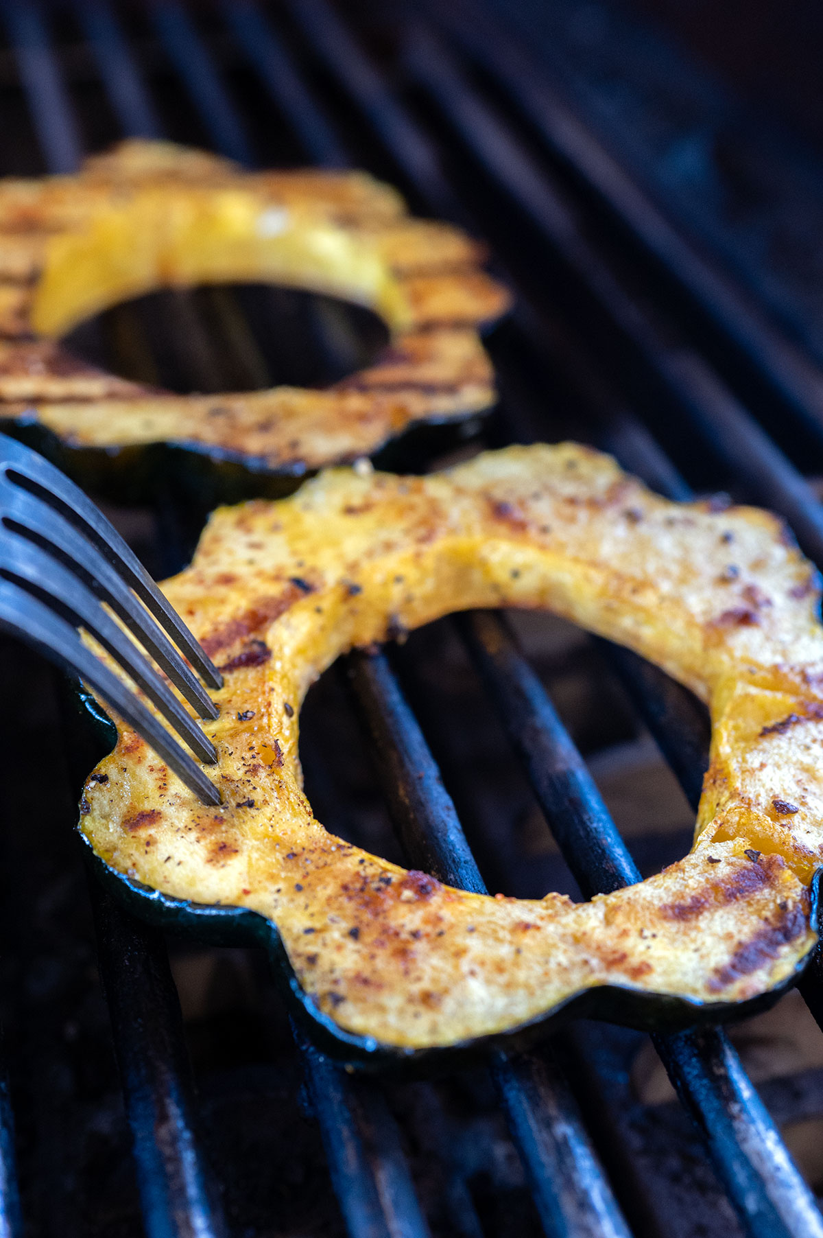 fork piercing into grilled acorn squash ring.