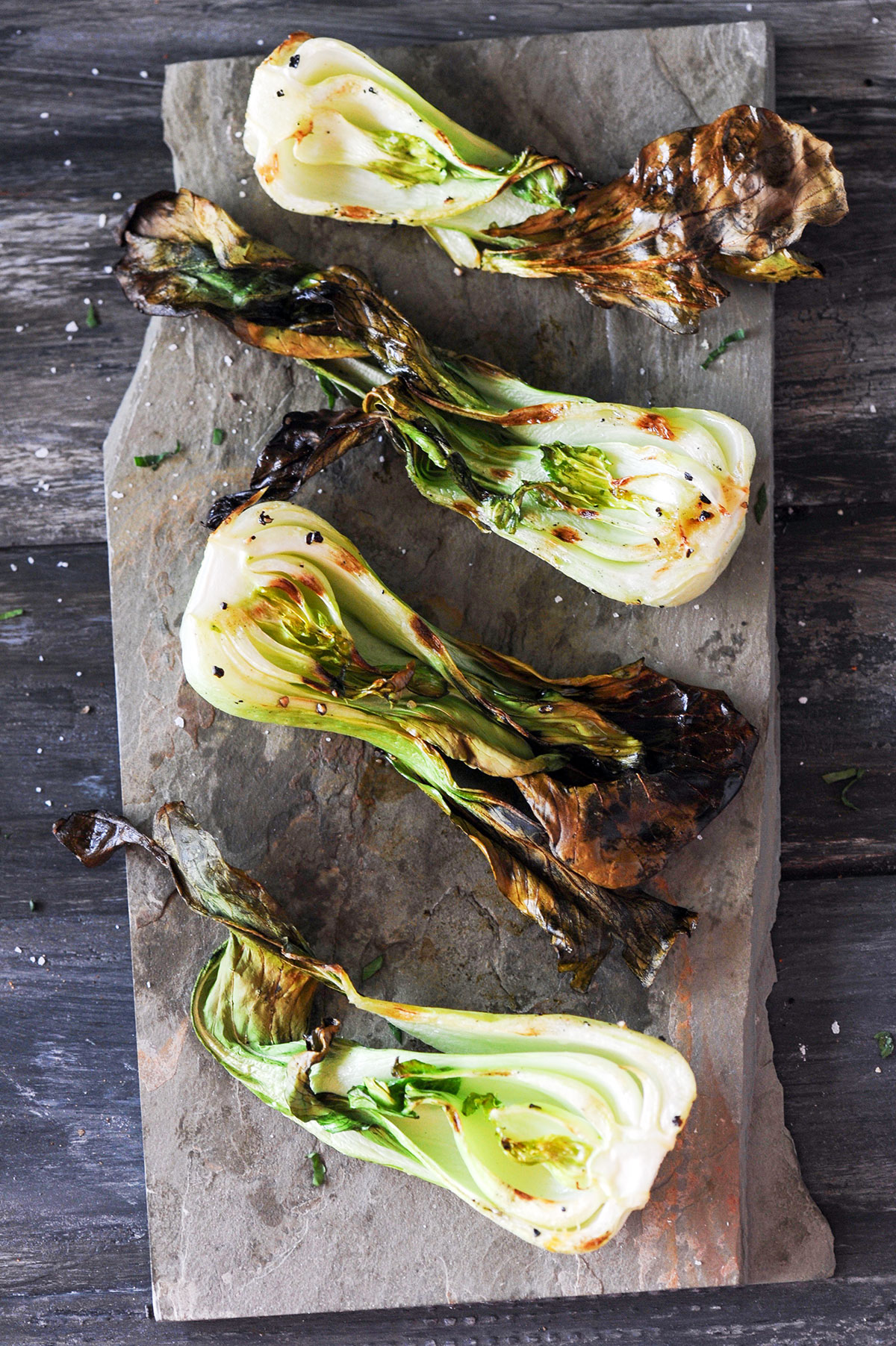 4 halves of grilled baby bok choy on slate. 