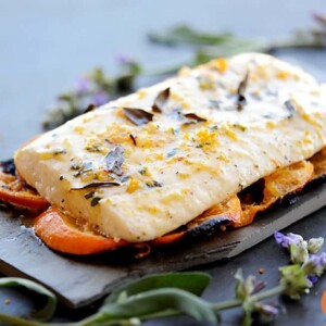 grilled halibut resting on tangarine slices with sage flowers