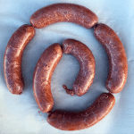 spiral of corned beef brisket sausages on white background