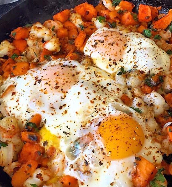 skillet with sweet potatoes and fried eggs
