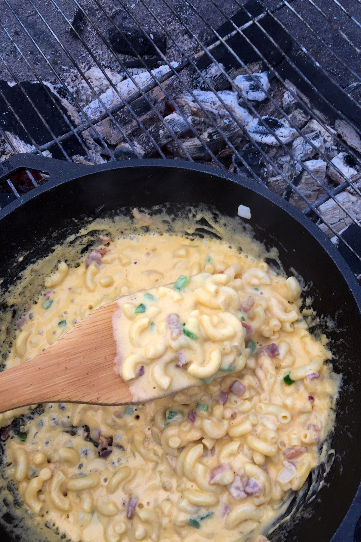 Wooden spoon scooping creamy mac and cheese.
