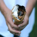 holding an ice cream cone with melted chocolate and marshmallows