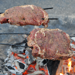 2 ribeyes on skewers over a campfire