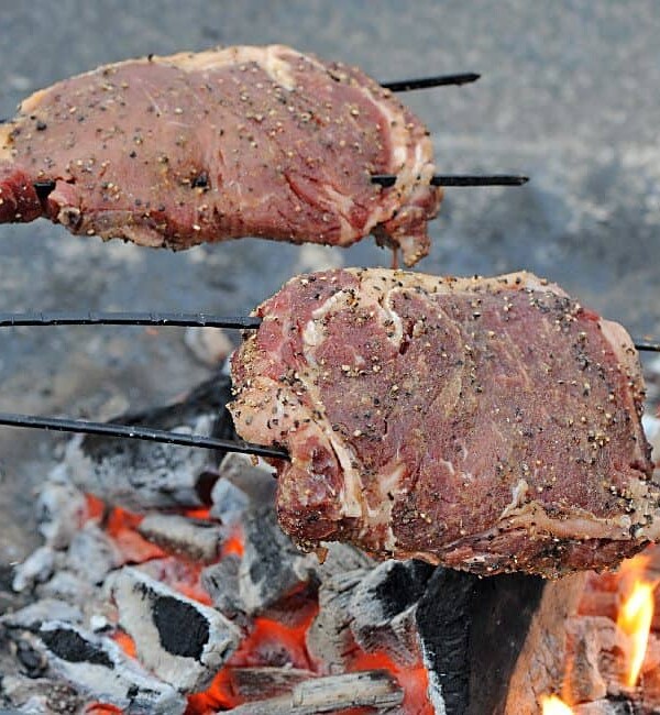 2 ribeyes on skewers over a campfire
