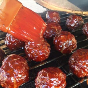 brushing sauce on meatballs on grill