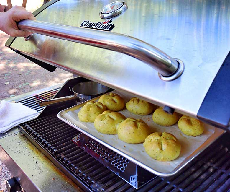 rolls baking on a grill with a pan resting on a veggie basket