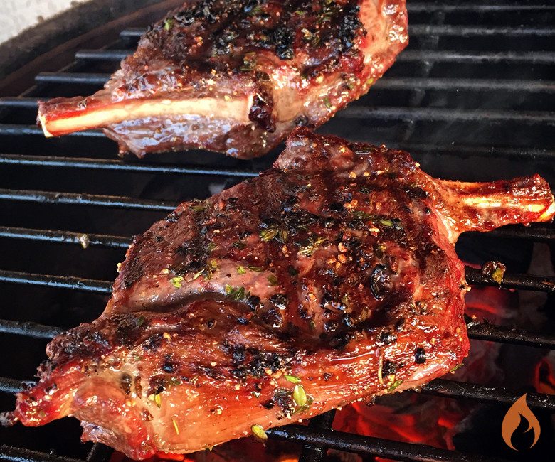 two elk chops grilling on a grill