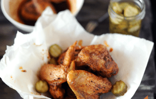 bowl of nashville hot chicken with sauce and pickles on side