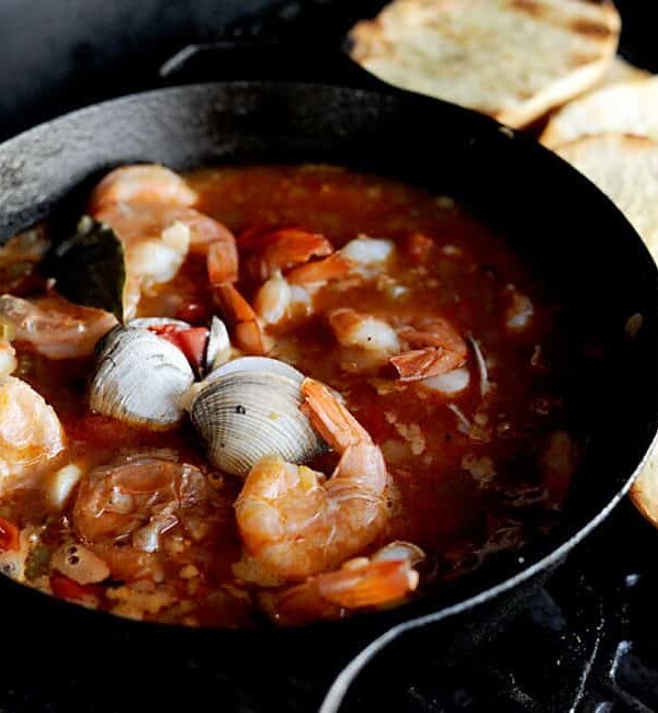 cast iron pot of grilled cioppino with toasted bread