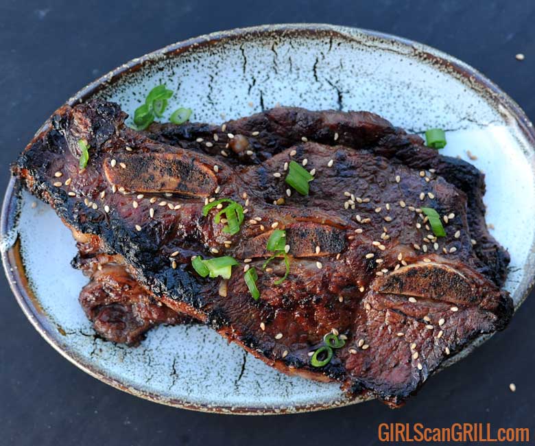gray plate of 3 kalbi ribs sprinkled with green onion