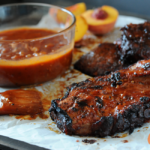 pork chops with bowl of peach bbq sauce to side