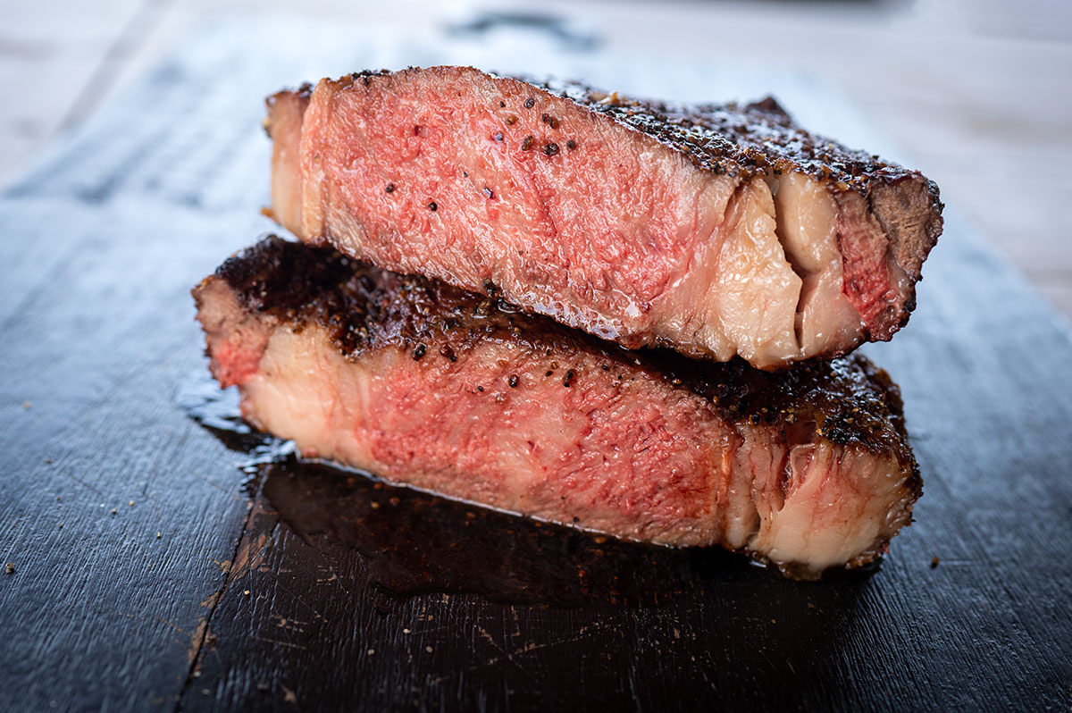 cowboy ribeye steak cut in half showing it's cooked medium rare.