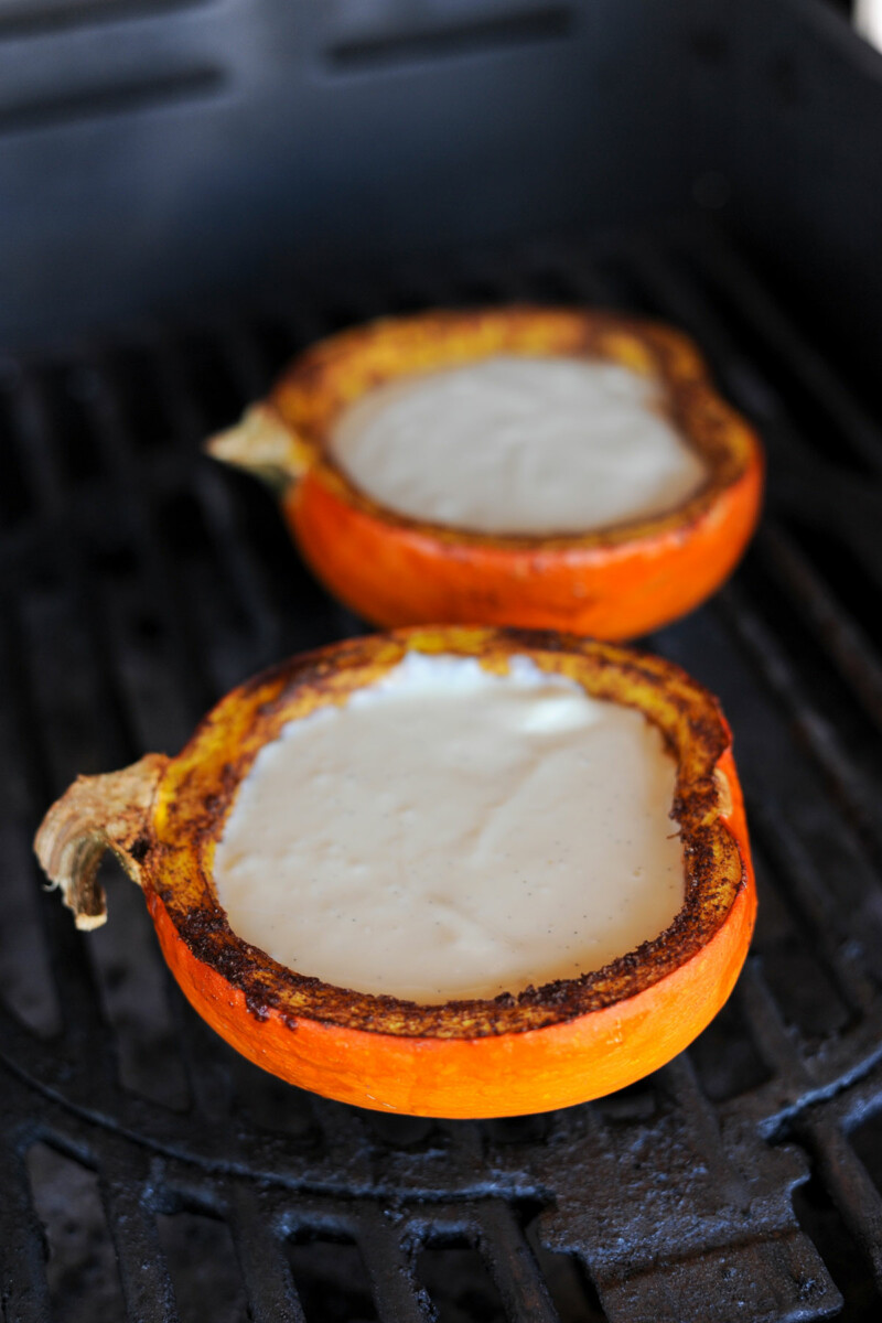 two pumpkin pie halves filled with cheesecake filling on the grill.