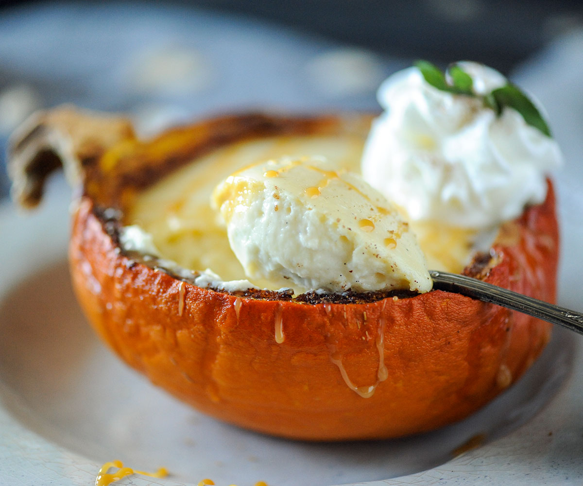 spoon scooping cheesecake out of a pumpkin shell.
