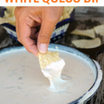 dipping chip into skillet of white queso dip.