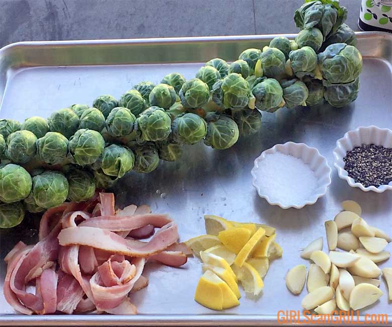 sheet pan with Brussels sprouts stalk, bacon strips, lemon and garlic