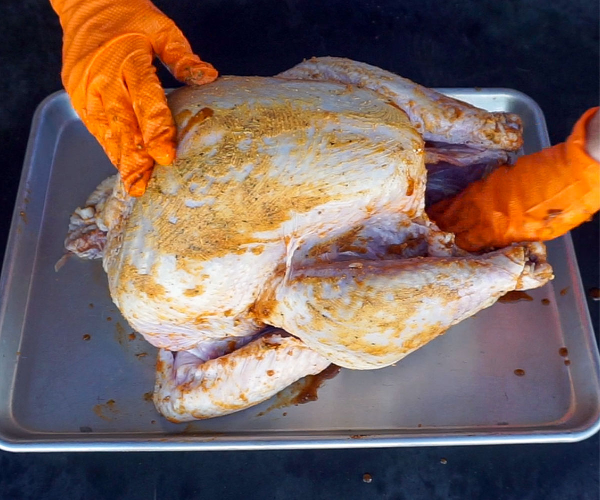 rubbing raw turkey with turkey rub.