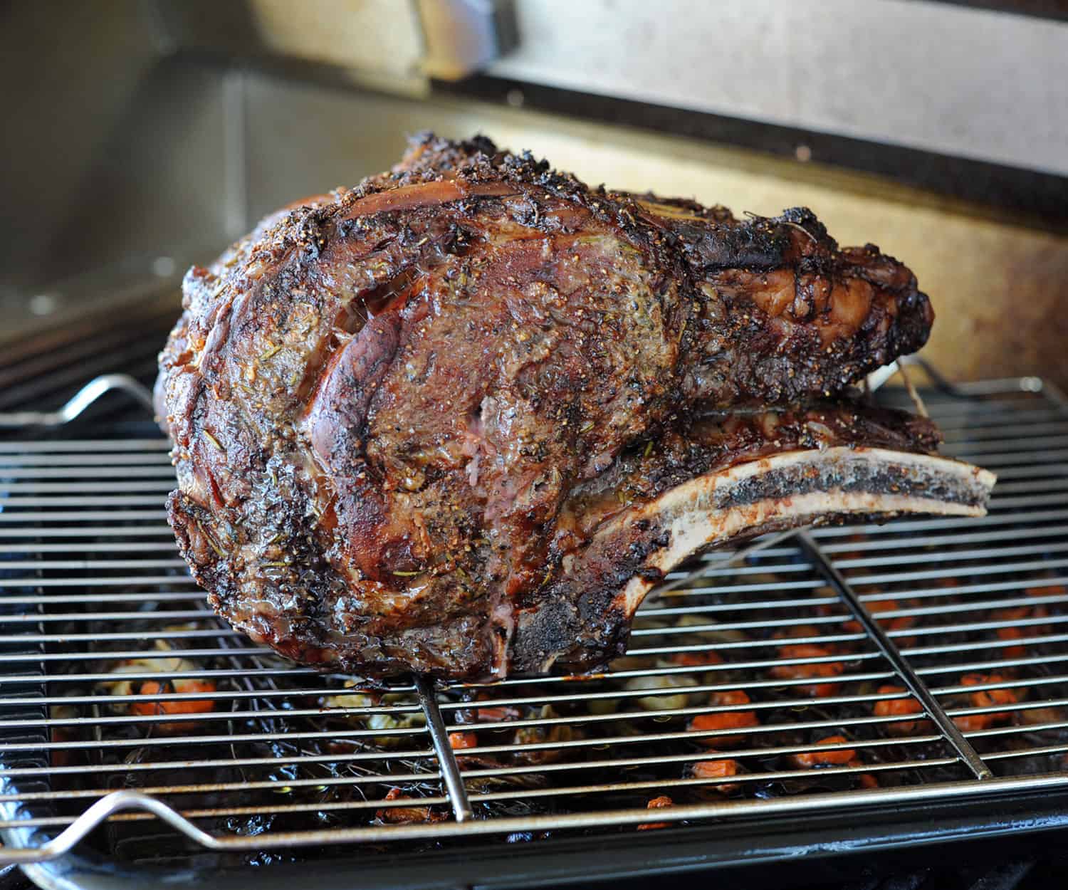 prime rib on grill over pan of vegetables