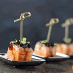 salmon cube on small plate with glaze on top and toothpick