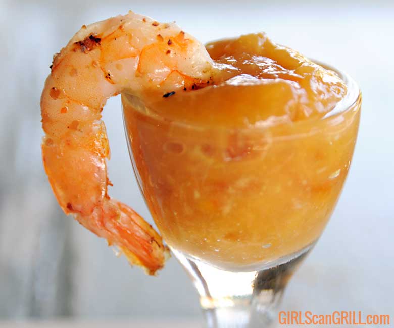 Grilled shrimp hanging from glass full of marmalade