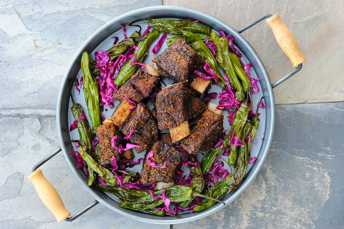 Smoked short ribs platter with shishito peppers and red cabbage.