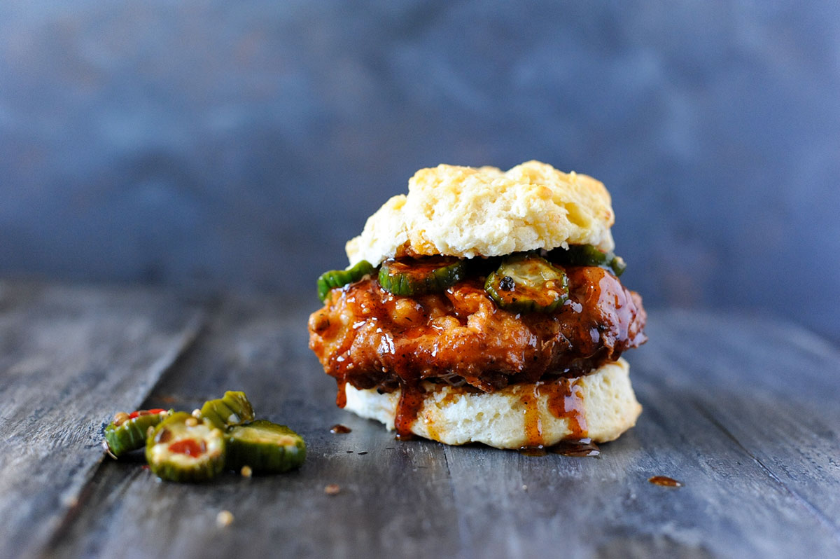 fried Nashville hot chicken on biscuit with hot honey and pickles. 