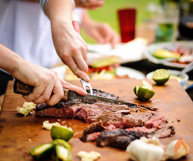 woman slicing cooked flank steak.