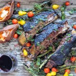three smoked beef ribs with fresh vegetables on platter with red wine