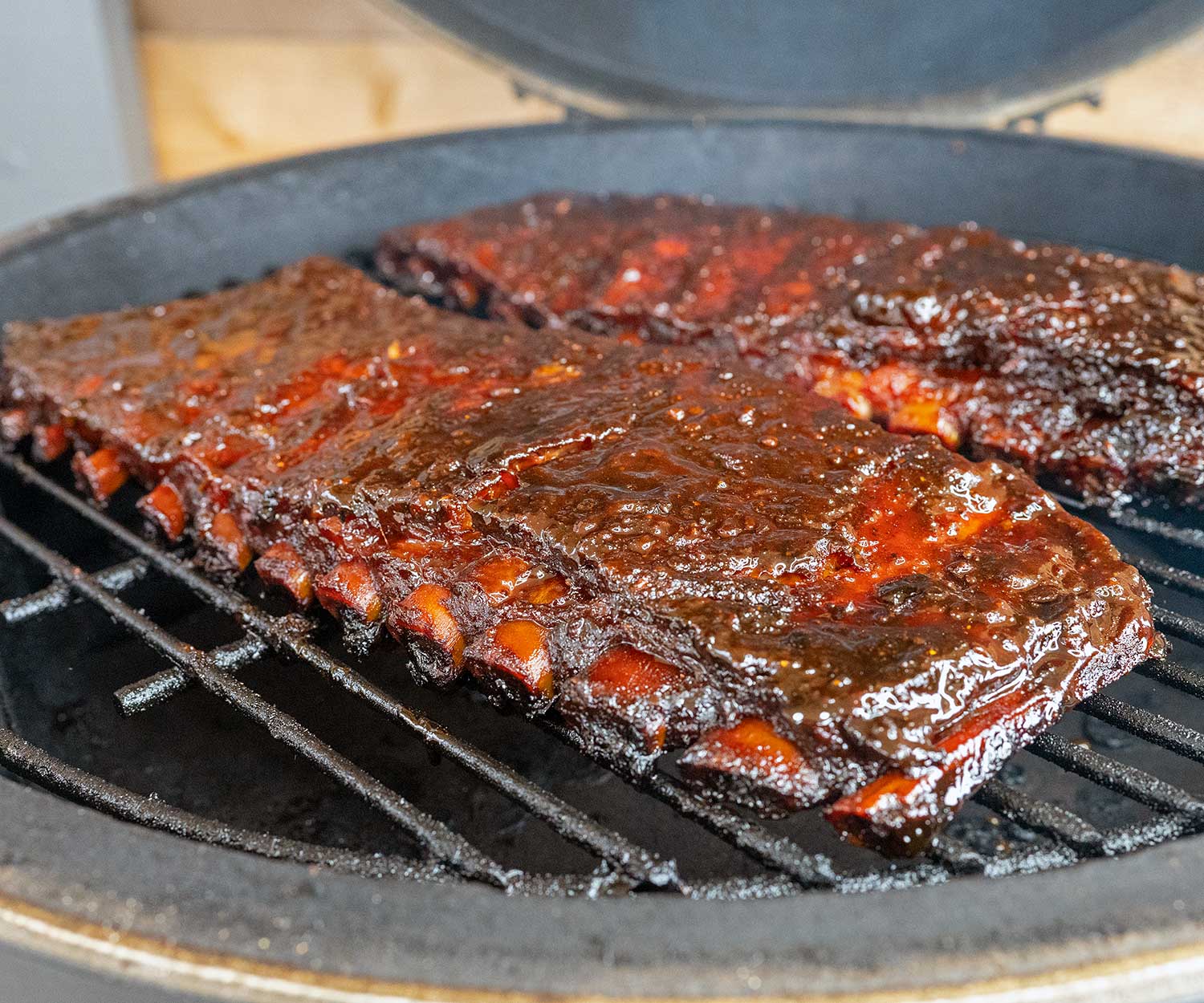 two racks of sauced ribs on grill