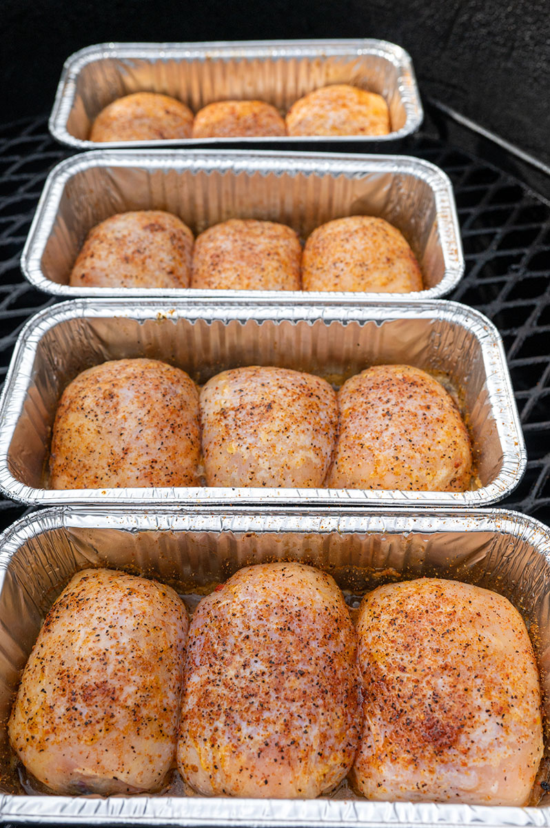 chicken thighs in loaf pans on grill.