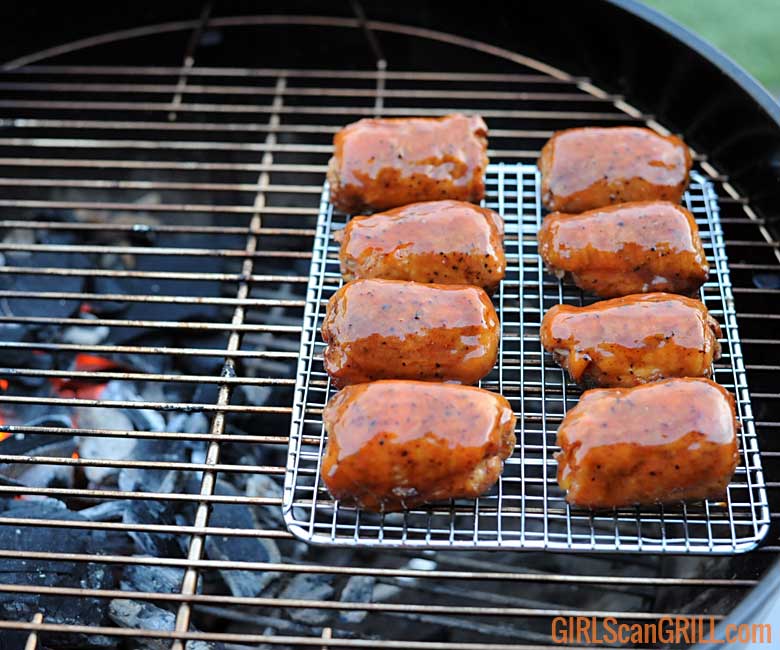 8 chicken thighs on a baking rack on a grill with coals to the left