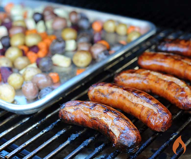 five sausages on grill next to pan of potatoes