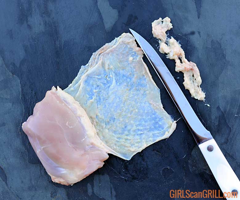 knife scraping underide of raw chicken thigh