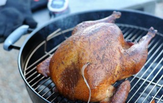 smoked turkey sitting on weber grill with igrill thermometer in breast