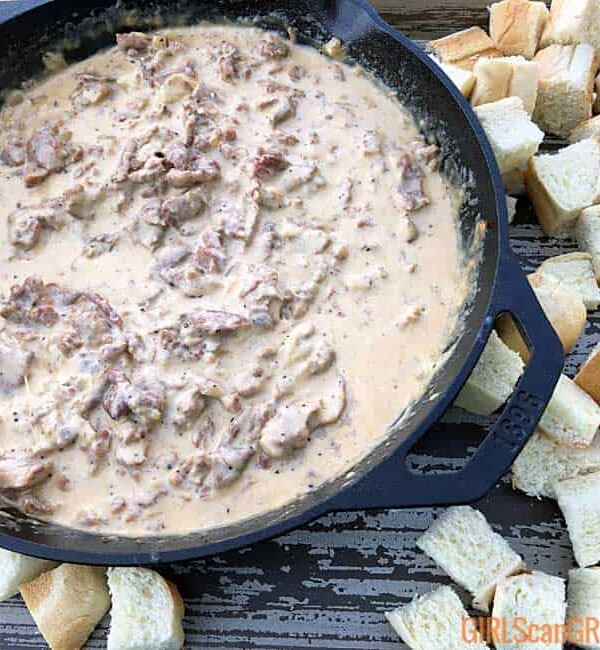 skillet of philly cheesesteak dip alongside bread cubes