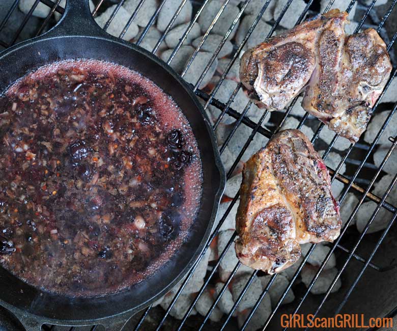 grill with cast iron on left with cherry sauce, two lamb chops on right