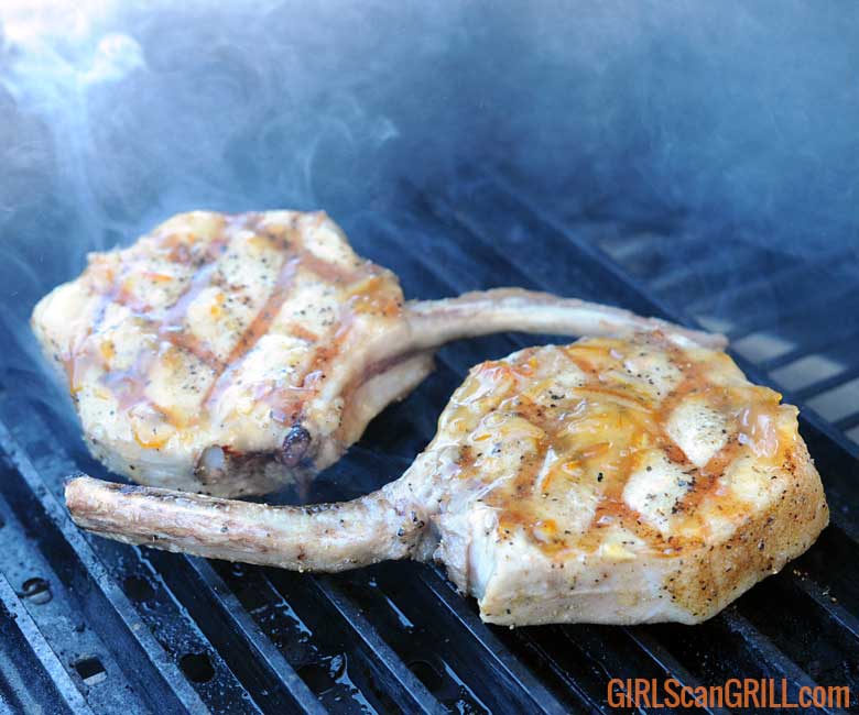 two pork chops on grill with grill marks and glaze