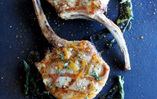 grilled pork chop on black plate with circle of glaze and asparagus